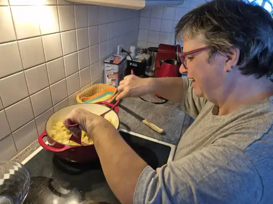 Barbara steht in der Küche und kocht mit Leidenschaft ein kreatives Gericht.